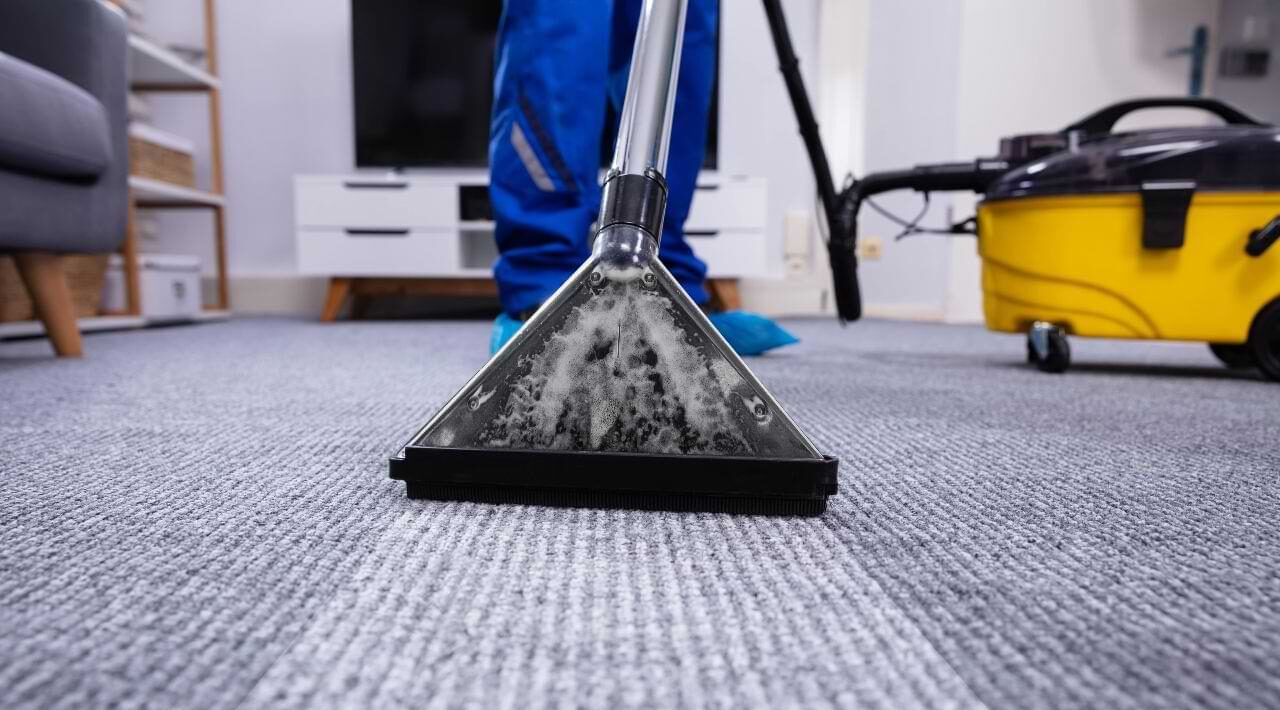 A cleaned maid is cleaning carpet with vaccum